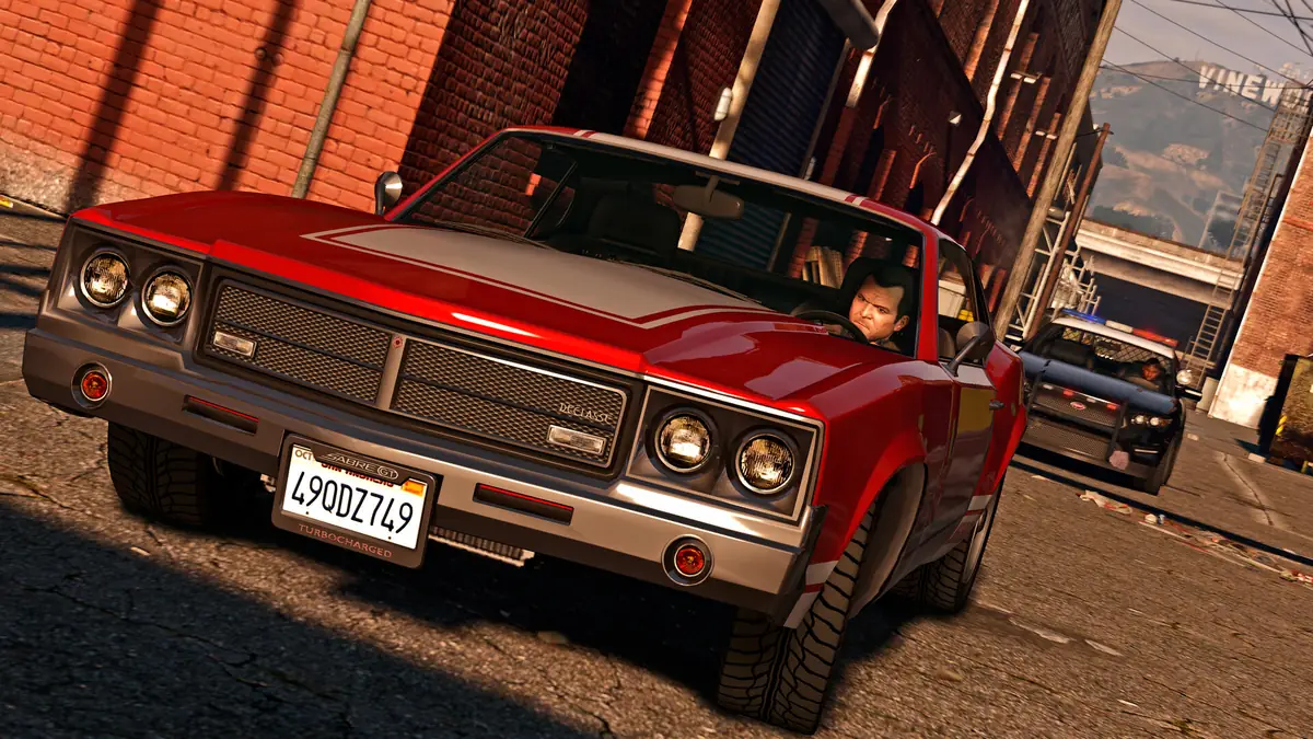 Michael huye en un muscle car rojo perseguido por la policía bajo el cartel de Vinewood