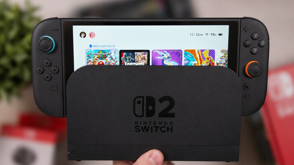 Nintendo Switch 2 negra en su dock sobre una mesa de madera, con anillos azul y naranja en los sticks