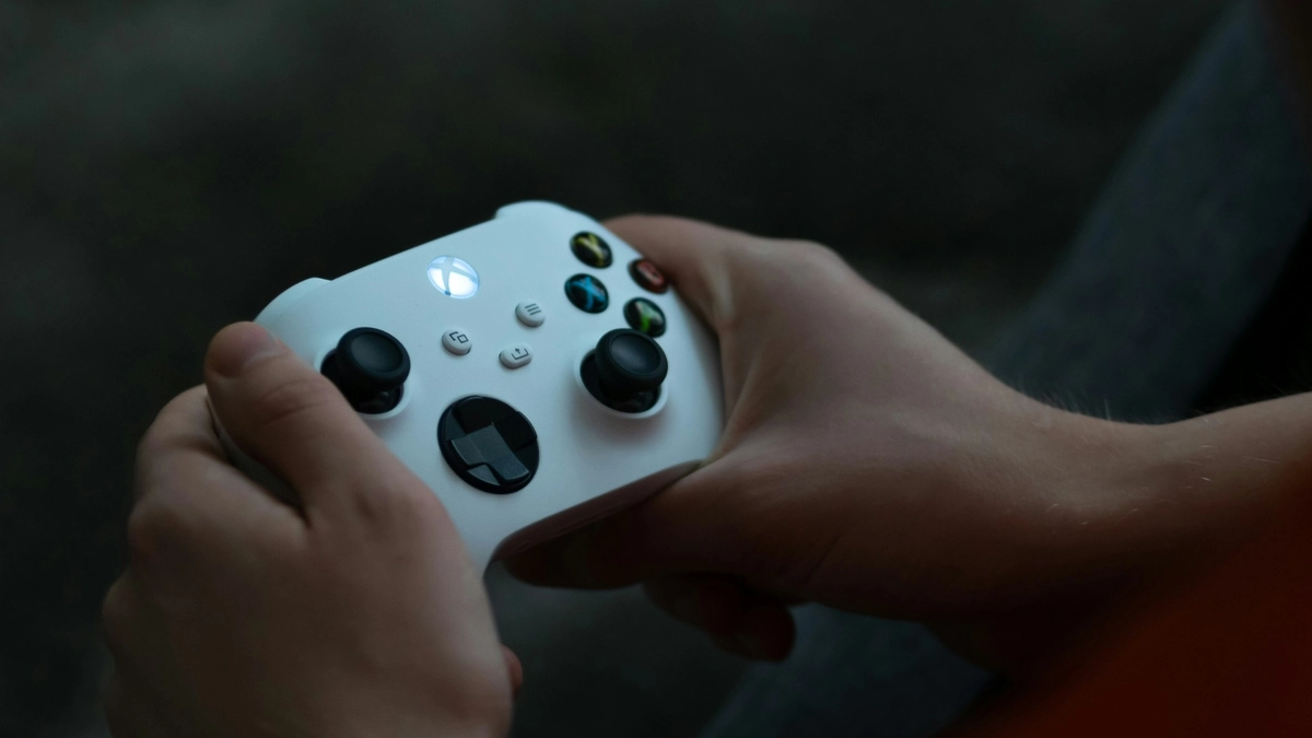 Manos sujetando un mando Xbox Series blanco con el botón Xbox encendido